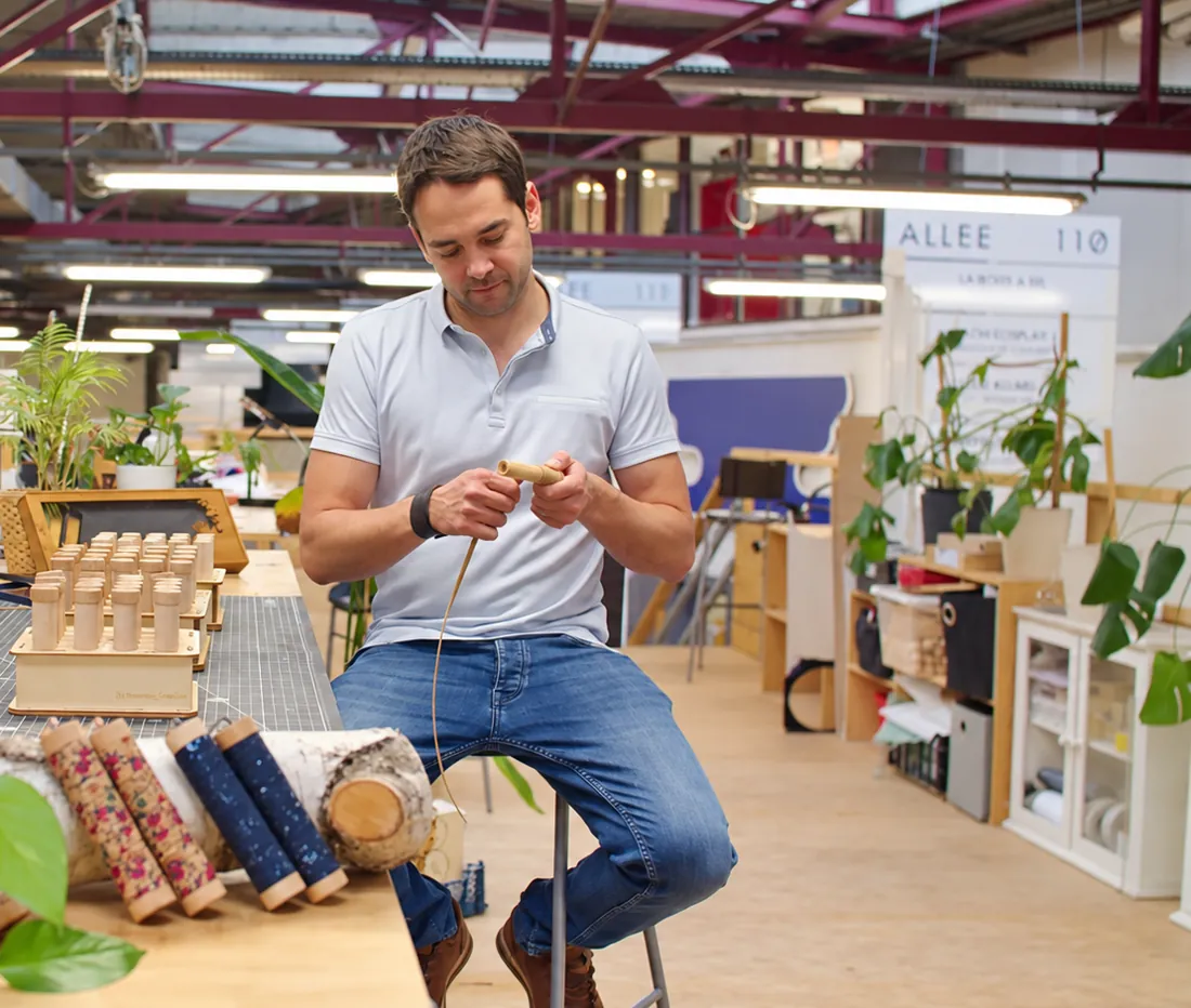 Guillaume, assis à l'établi de son atelier, façonne une poignée de baguette.