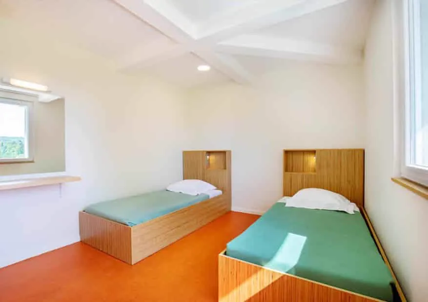 Une chambre du pavillon, lumineuse, avec deux lits.